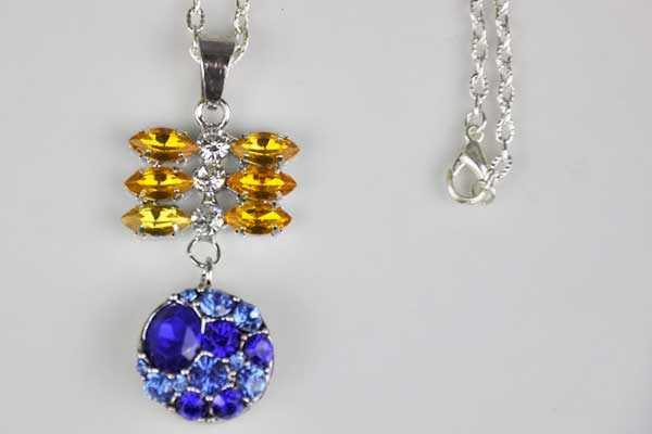 Halskette silber mit grossem Anhänger mit vielen Kristallen und einem Chunk-Button integriert, gelb-blau